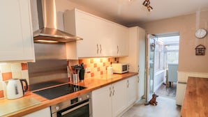 A modern kitchen with white cabinets, a stainless steel range hood, a microwave, and an oven. - Willow Nook (Whitby)