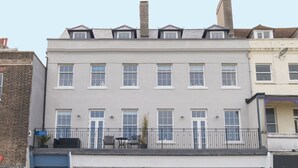 A two-story building with a balcony, multiple windows, and a small outdoor seating area. - 6 The Beaches (Weymouth)