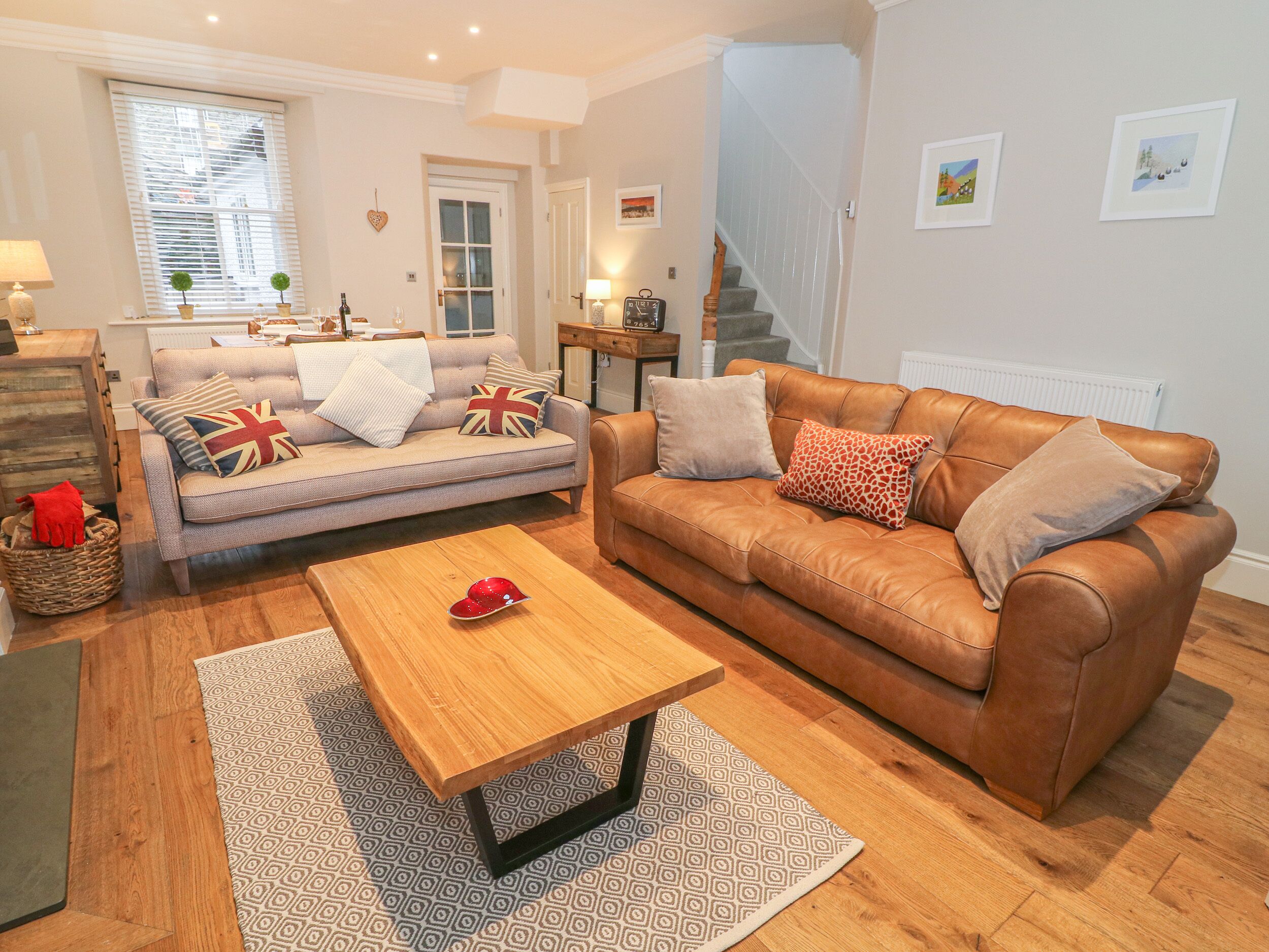 A cozy living room with a sofa, a brown leather couch, a wooden coffee table, and a patterned rug.