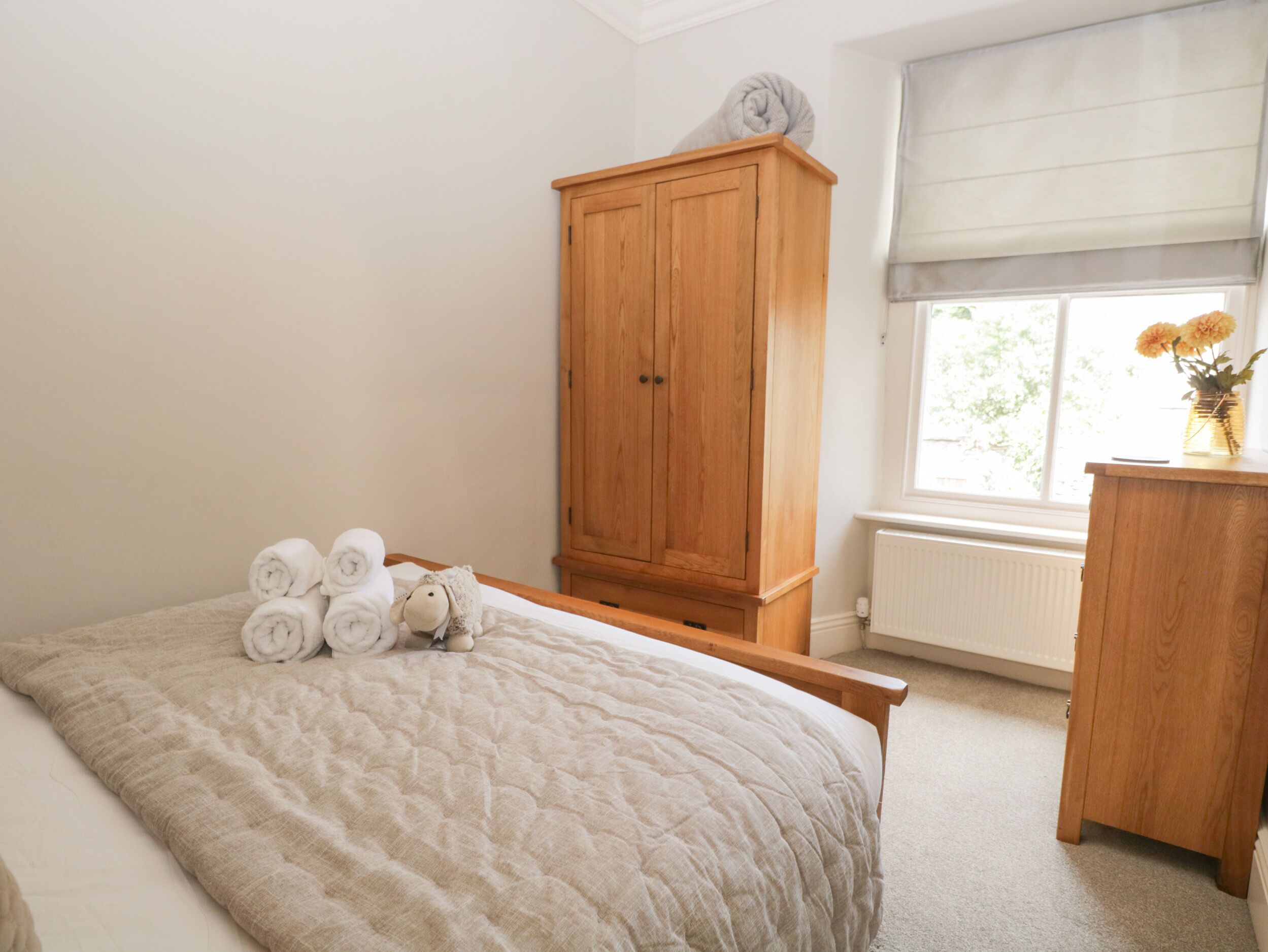 A bedroom with a bed, a wooden wardrobe, and a window with a view.