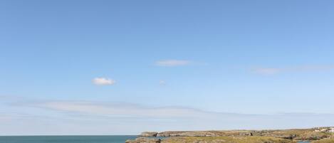 A coastal landscape with rocky terrain and a clear sky.