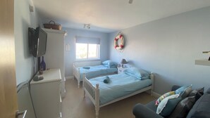 Un dormitorio con dos camas, televisión, calefacción, ventana y ventilador de techo.