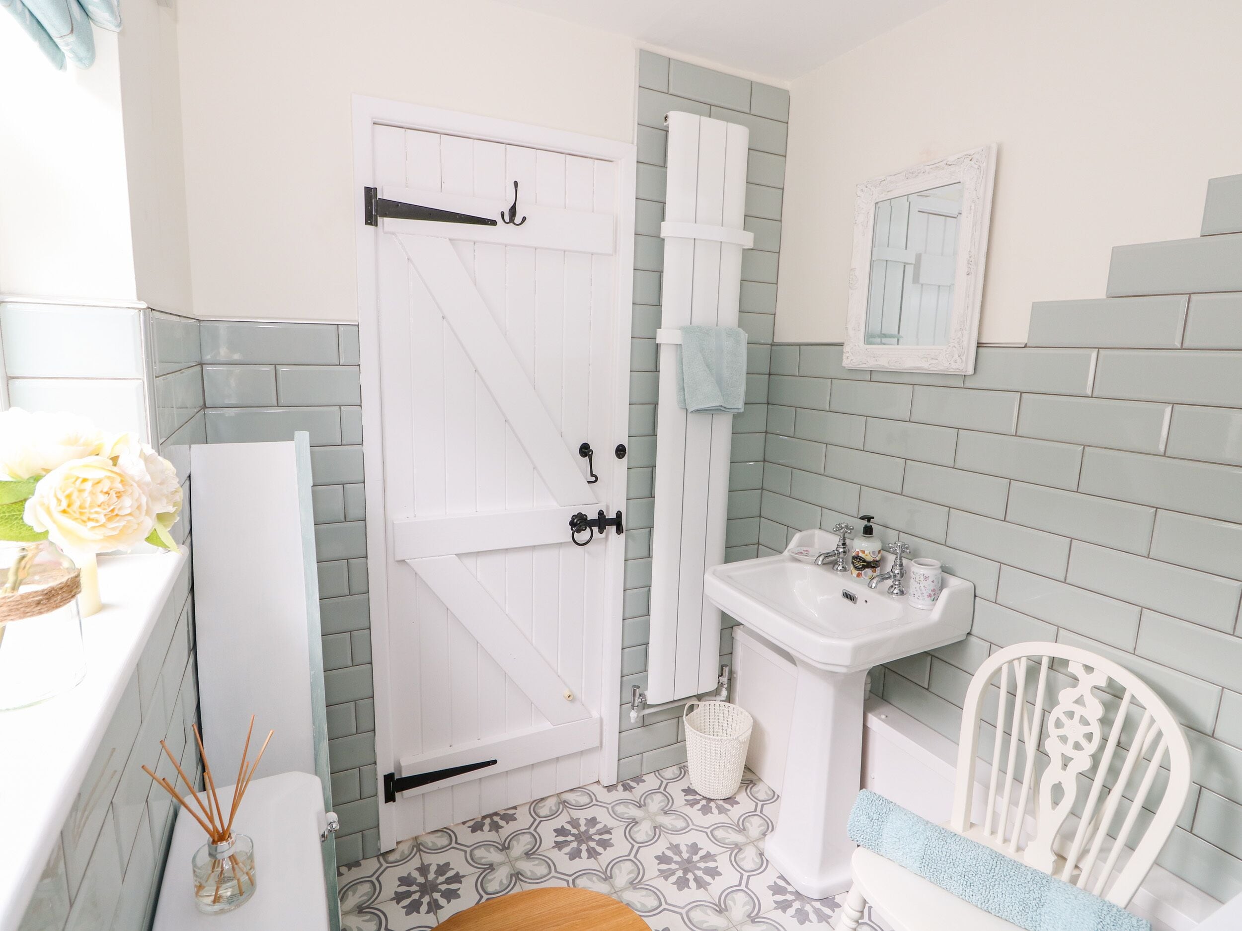 A bathroom with a white door, a sink, a mirror, and a patterned floor.