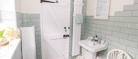 A bathroom with a white door, a sink, a mirror, and a patterned floor.