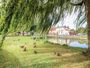Guests can enjoy a serene riverside setting with a grassy area and a traditional building in the background.
