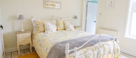 A bedroom with a bed, nightstands, a window, and a door.