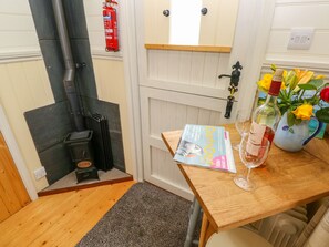 Une pièce chaleureuse avec une table en bois, un magazine, un verre à vin et un vase rempli de fleurs.