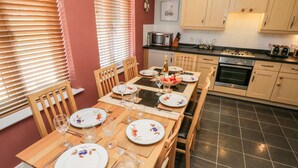 A dining area with a wooden table set for four, surrounded by chairs.