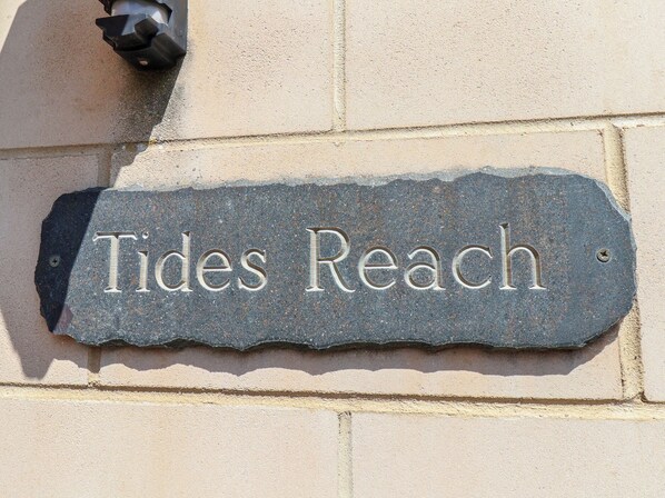 A stone sign with the inscription 'Tides Reach' mounted on a building wall. - Tides Reach (Whitby)