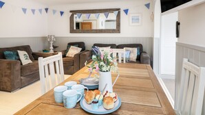 Ein Essbereich mit einem Holztisch, gedeckt für ein Frühstück, inklusive Muffins, Scones und Tee.