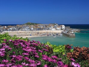A coastal town with a beach, boats, and a lighthouse.