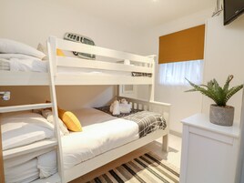 Habitación con literas, una ventana, una planta y un televisor.