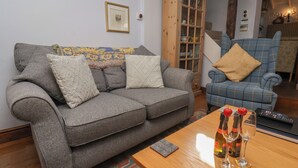 A living room with a grey sofa, a blue armchair, and a wooden cabinet.