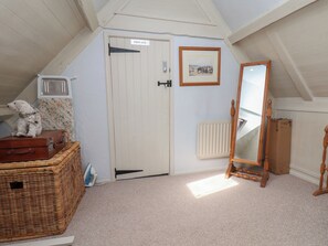 A room with a sloped ceiling, a white door labeled 'PRIVATE,' a framed picture on the wall, a wooden mirror, and a wicker chest of drawers.