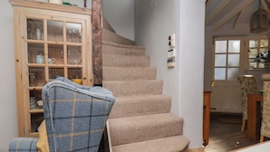 A staircase with a wooden cabinet and a chair with a plaid blanket. - Cobbles House (Whitby)
