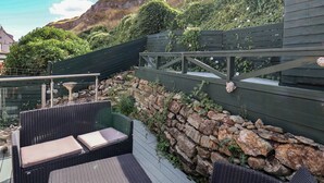 A rooftop garden with a seating area, stone wall, and a view of the surrounding landscape.