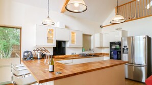 A modern kitchen with a central island, stainless steel appliances, and pendant lighting. - Dorado Lodge (Lincoln)
