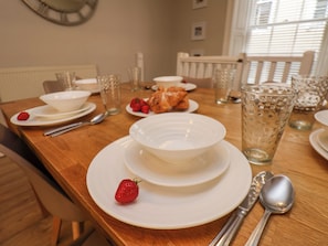 Enjoy a casual meal at this inviting table setting, complete with fine china, glasses, and a fresh strawberry.