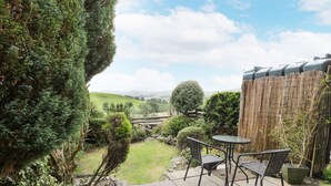 A patio with stone flooring and a round table with two chairs. - Plas Arenig (Blaenau Ffestiniog)
