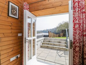 Un intérieur en bois donnant sur un lac, avec un escalier menant à l’extérieur.