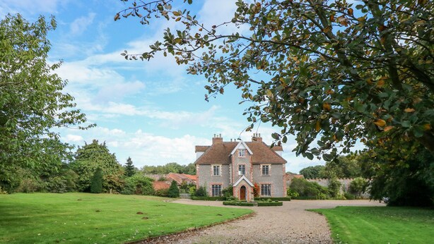 A large, historic house with a gravel driveway leading to a well-maintained lawn and garden. - Southrepps Lodge (Norwich)