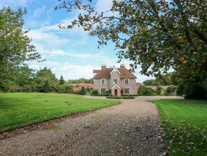 A large, historic house with a gravel driveway leading to a well-maintained lawn and garden. - Southrepps Lodge (Norwich)