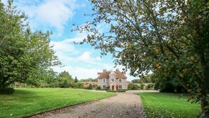 A large, traditional house with a gravel driveway leading to a well-maintained lawn and a formal garden. - Southrepps Lodge (Norwich)