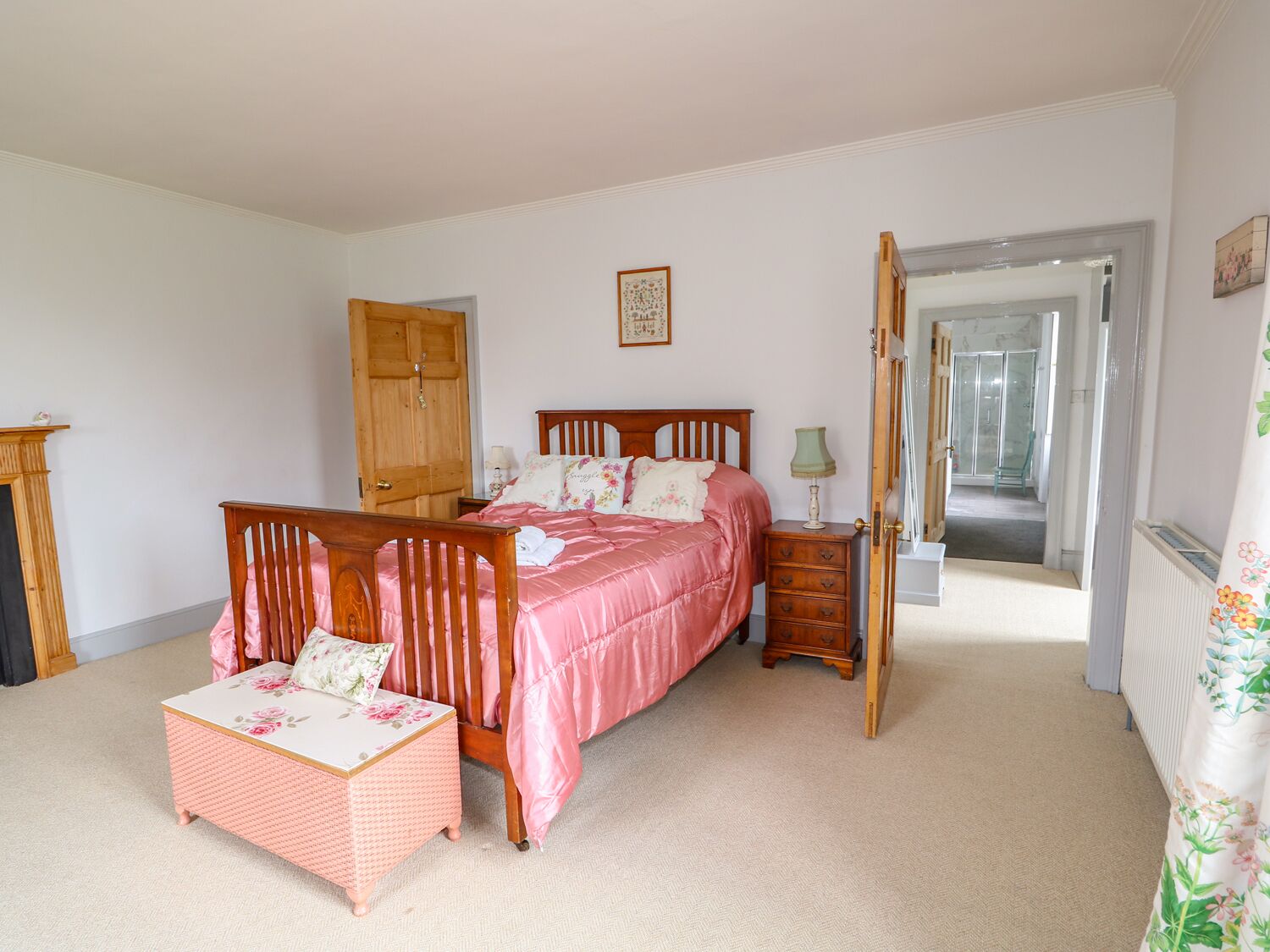 Un dormitorio con cama de madera, una silla de madera, una mesita y un armario.