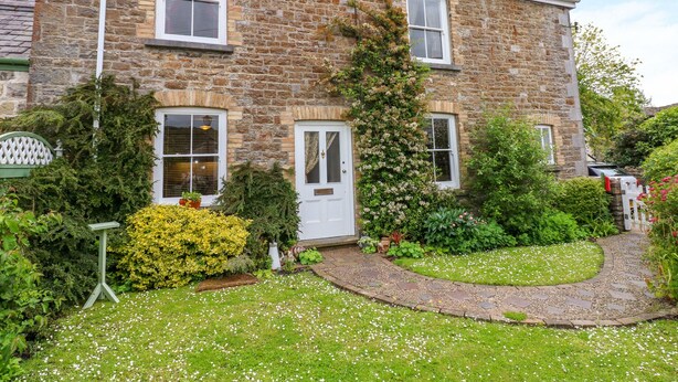 A stone building with a garden in front. - Castle School House (Kidwelly)