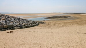 A beach with a rocky breakwater and a sandy shore. - Castle School House (Kidwelly)