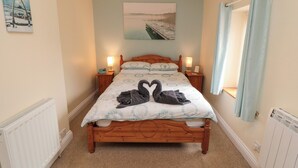 A bedroom with a wooden bed, two bedside tables with lamps, a radiator, and a wall-mounted picture.