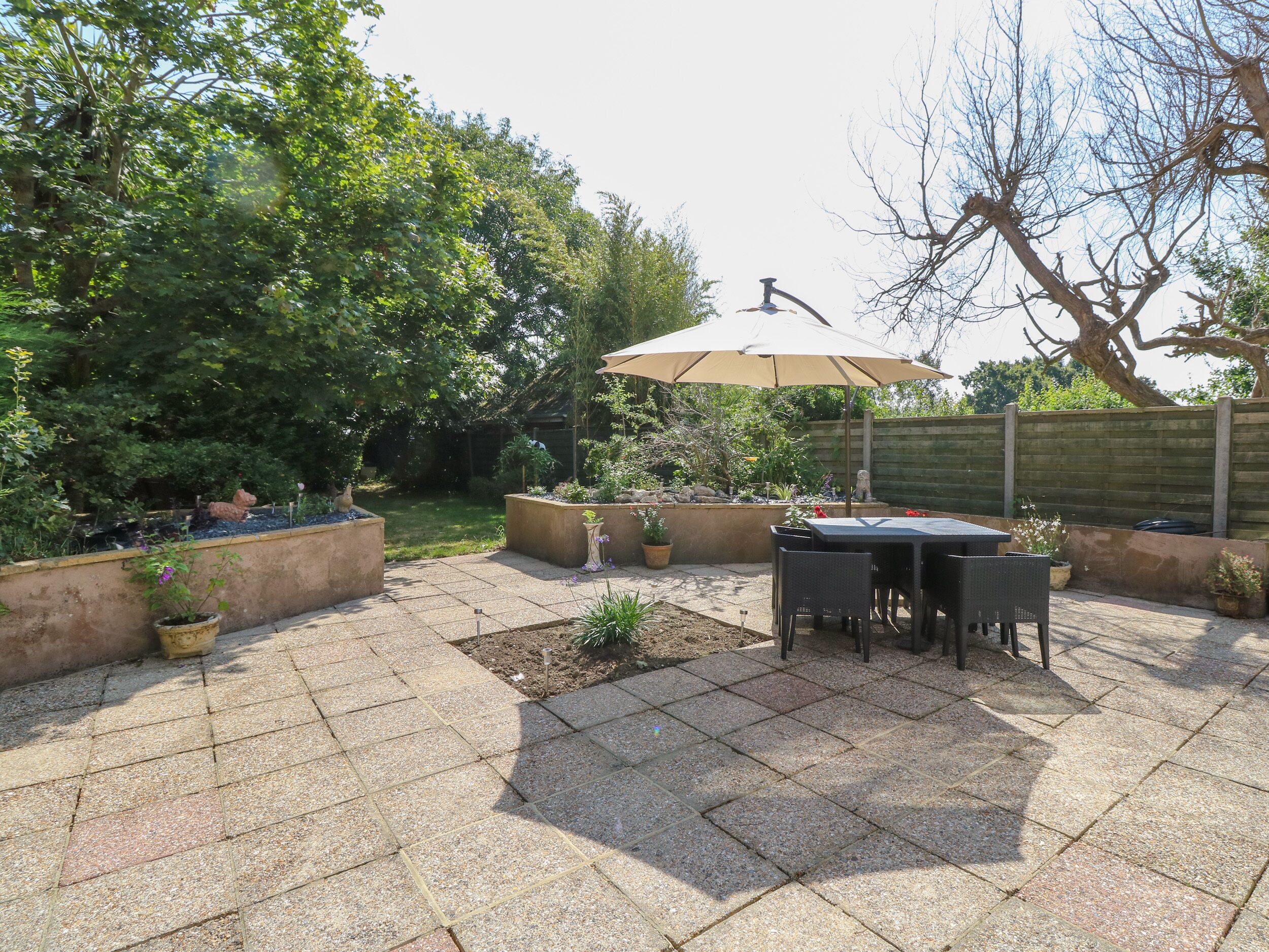 Une terrasse avec une table et des chaises, entourée de jardinières et d’une clôture en bois.