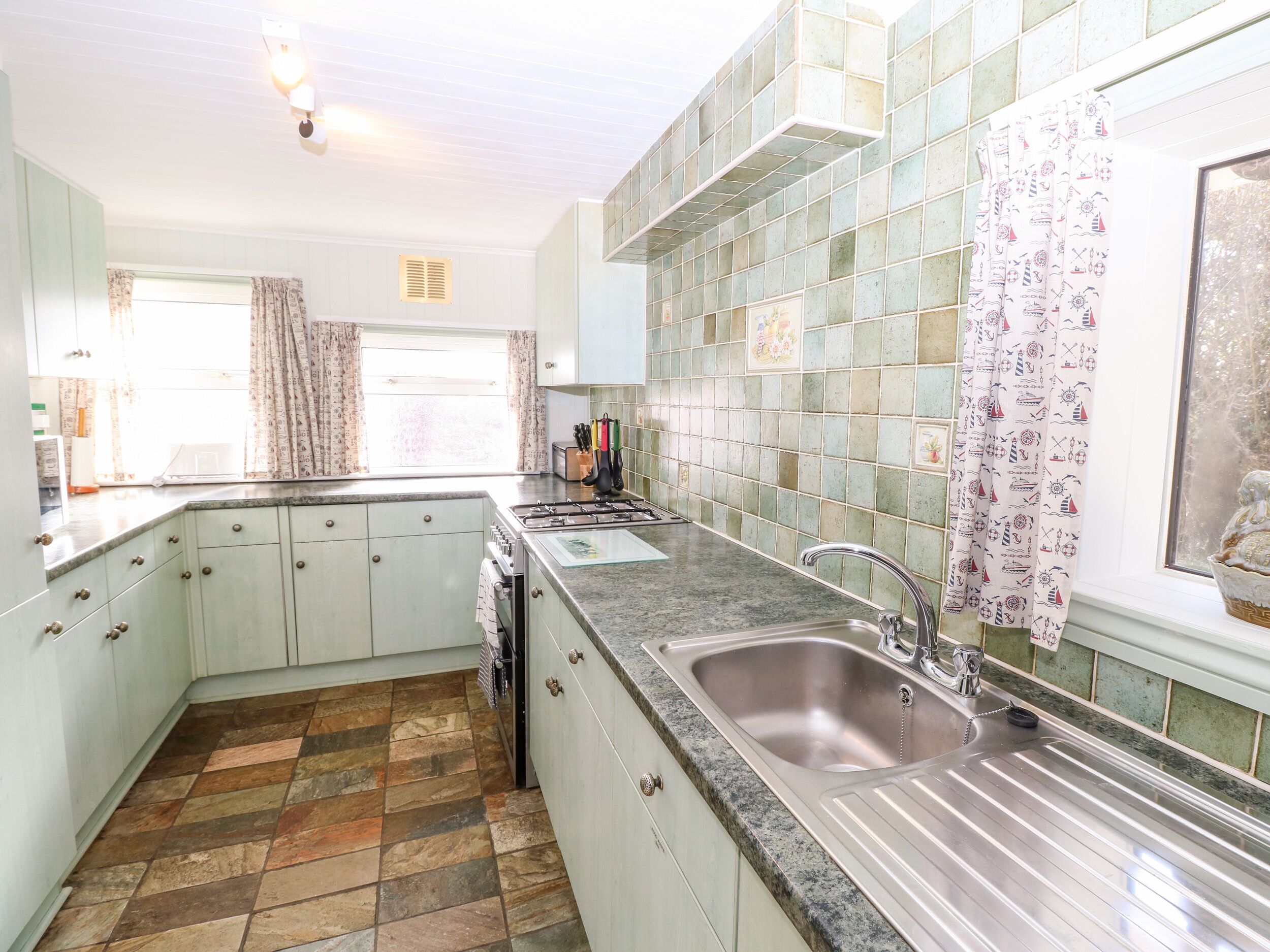 A kitchen with a granite countertop, stainless steel sink, and a tiled backsplash.