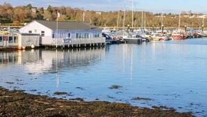A waterfront seafood restaurant with a dock extending into calm water, surrounded by boats and a clear sky. - St. Michaels House (Ryde)