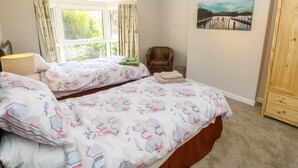 A bedroom with two beds, a window with curtains, a chair, a painting, and a wardrobe. - St. Michaels House (Ryde)