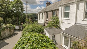 Una calle residencial con casas, una vía pavimentada y abundante vegetación.