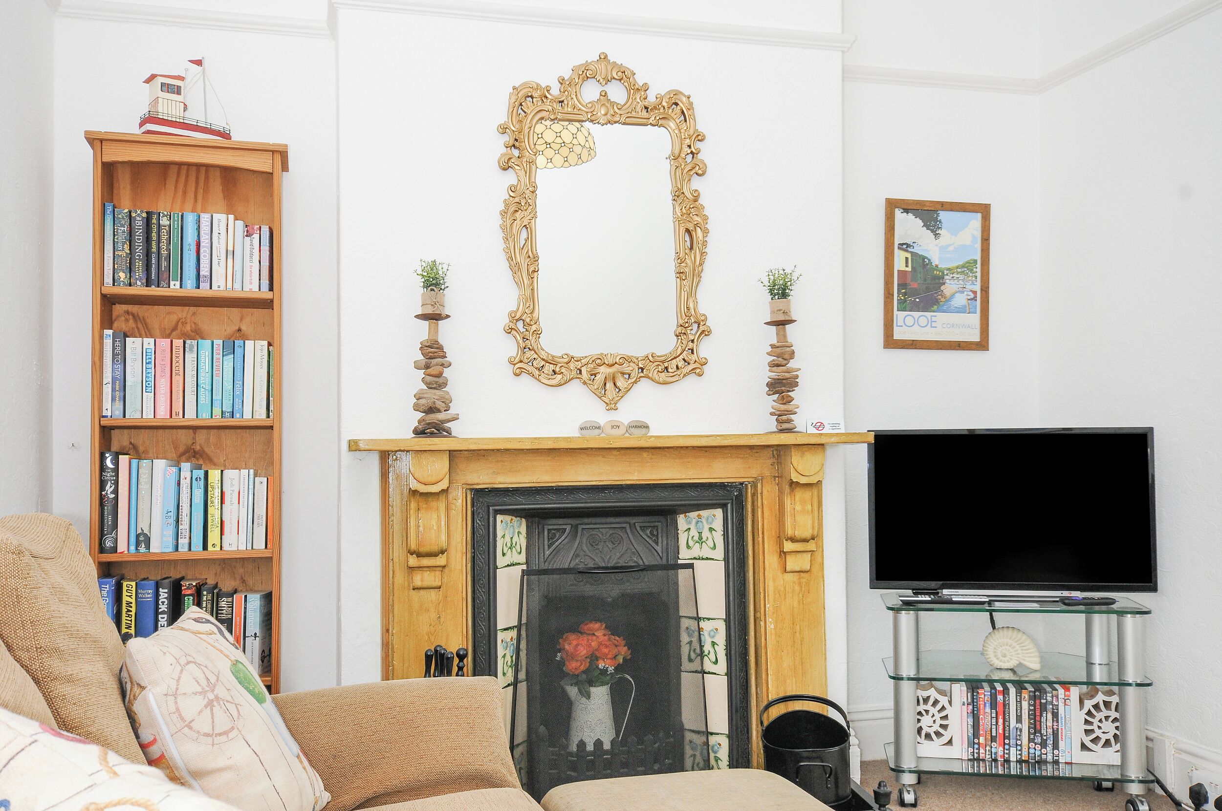 A living room with a fireplace, a bookshelf, a TV, and a framed picture on the wall.