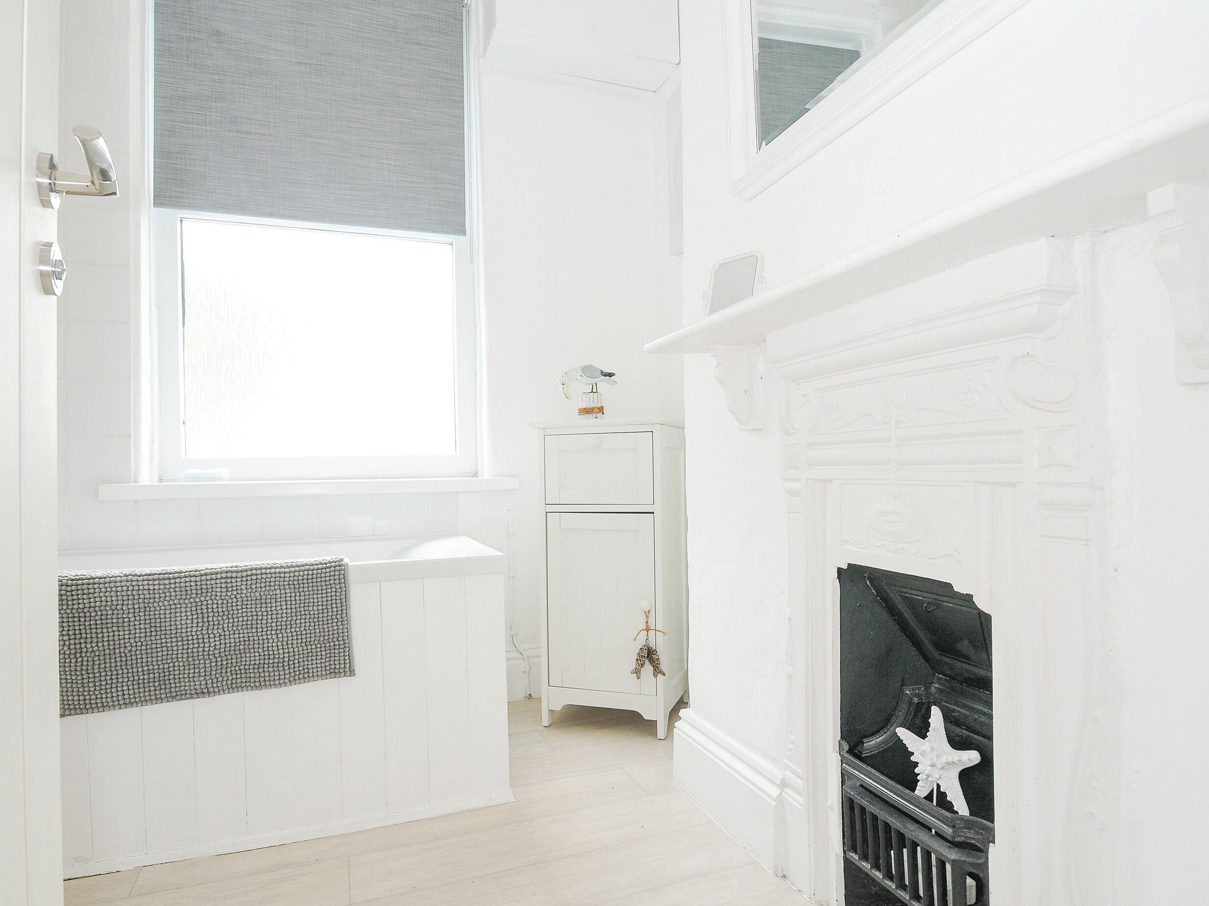 A white room with a fireplace, a radiator, and a window with blinds.