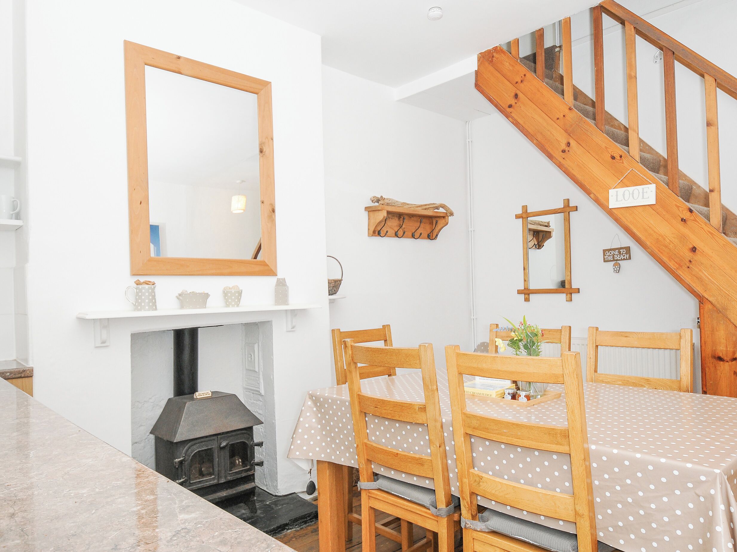 A cozy dining area with a wooden table and chairs, a fireplace, and a wooden staircase.