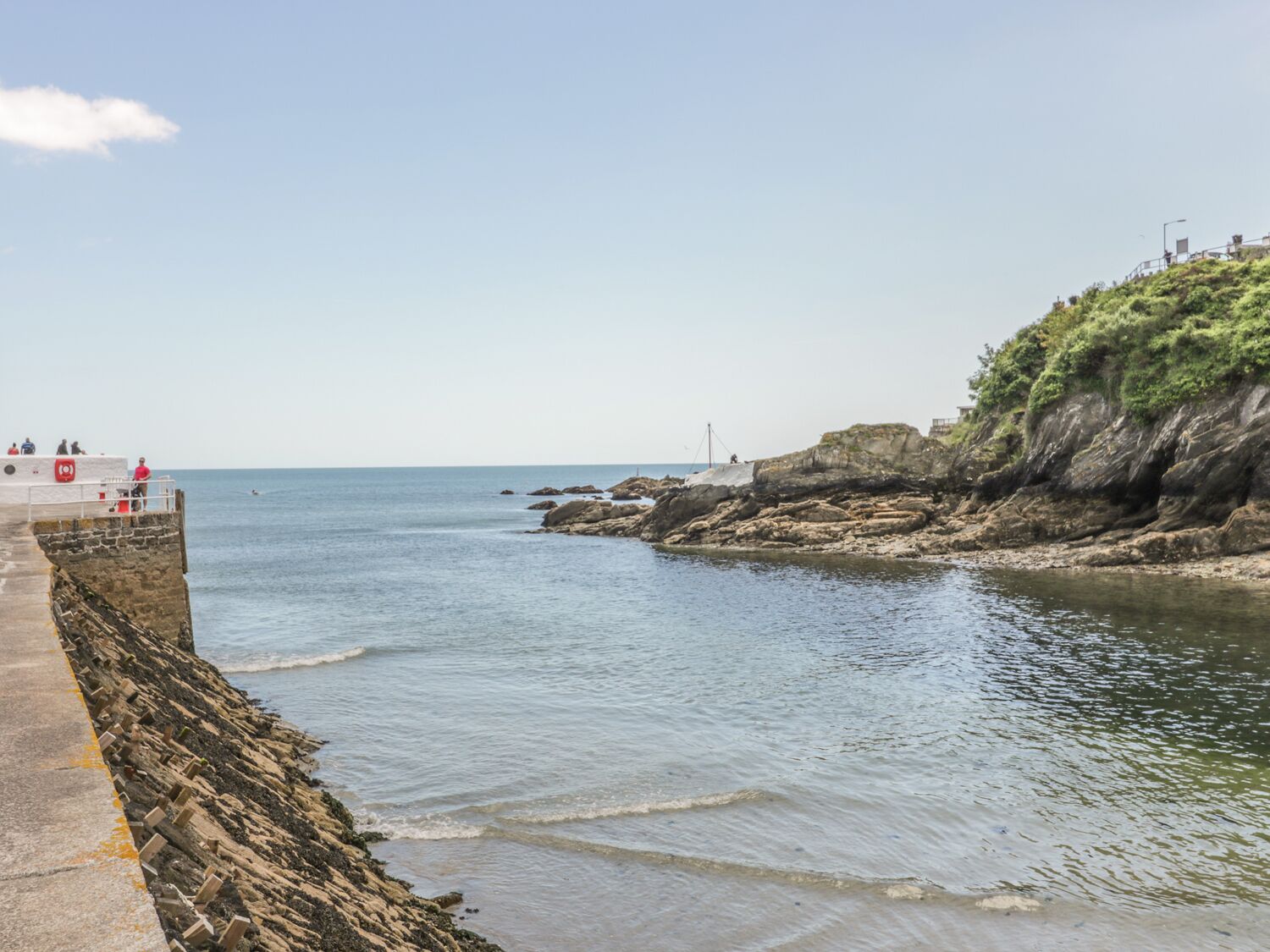 Une promenade en bord de mer, avec une falaise rocheuse et une vue dégagée sur l’océan.