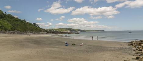 A beach with a rocky shoreline, clear skies, and a few boats on the sand.