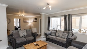 A living room with two sofas, a wooden coffee table, and a lamp. - Tennyson House (Scarborough)
