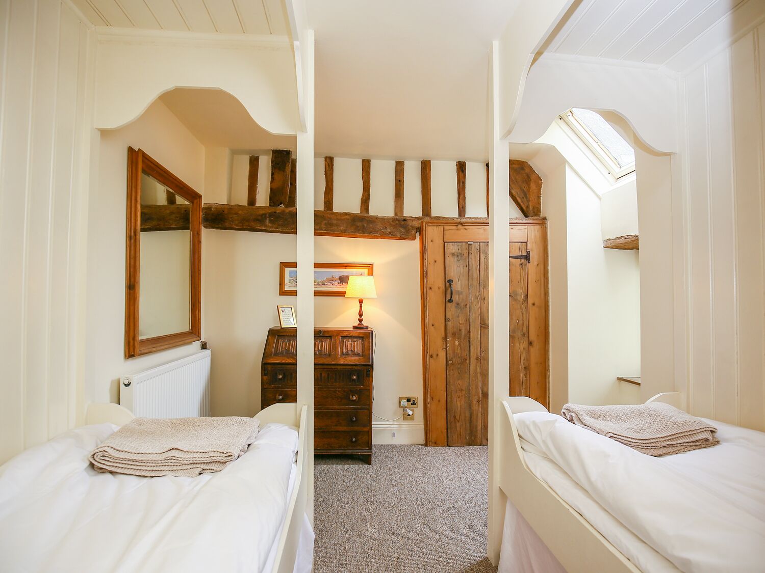 Una camera da letto con due letti, un armadio in legno, una cassettiera e uno specchio.
