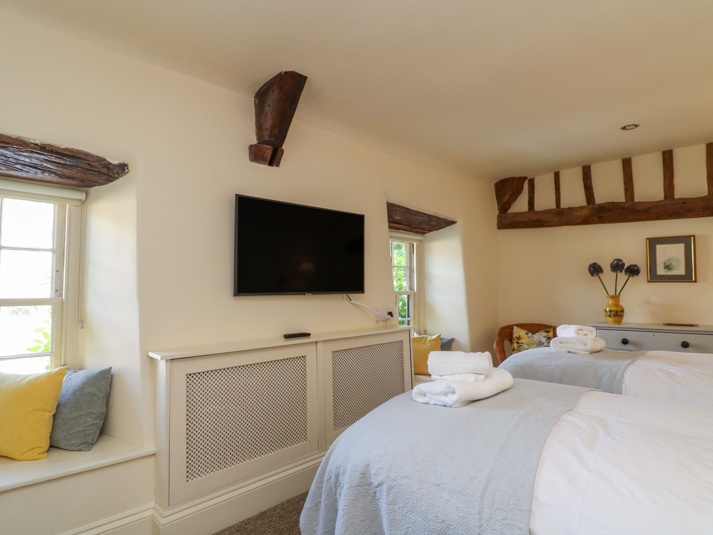 A hotel room with two beds, a television, a window, and a fireplace.