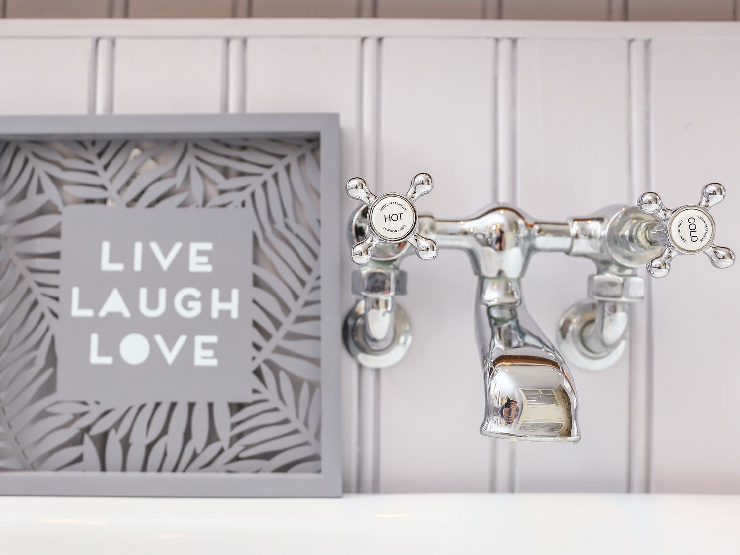 A bathroom with a framed motivational quote, a modern faucet, and a mirror.