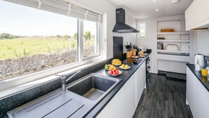 Una cocina moderna con un ventanal grande, una encimera negra y vistas a un campo verde.