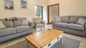 A spacious living room with two grey sofas, a wooden coffee table, and a patterned rug. - The Milking Barn (Yeovil)