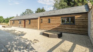 A log cabin with a gravel driveway and a wooden deck. - The Milking Barn (Yeovil)