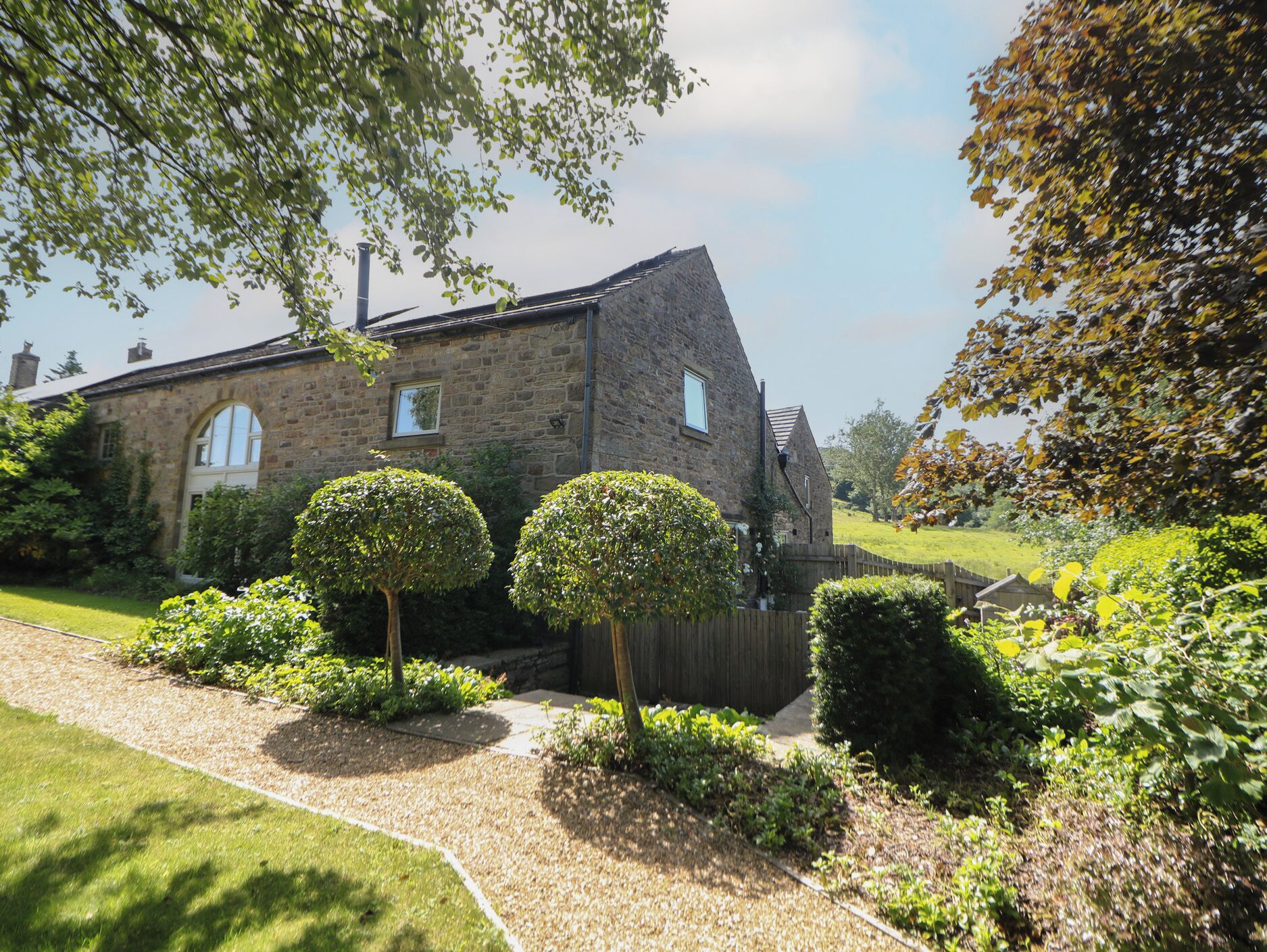 A stone building with a traditional design, a paved driveway, and well-maintained hedges.
