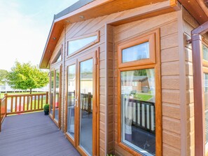 Fachada de madera con ventanas amplias y una terraza.